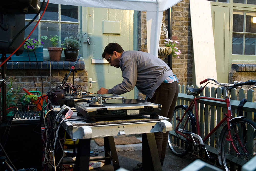 musician performing on turntables outdoors under a tent